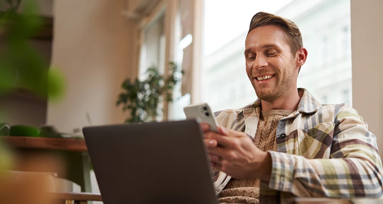 close up portrait handsome smiling man with laptop cafe visitor sitting chair using smartphone 1